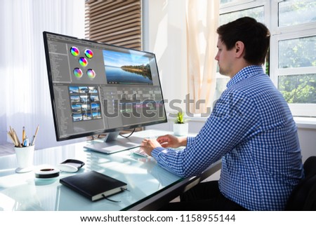 Young male editor editing video on computer at workplace