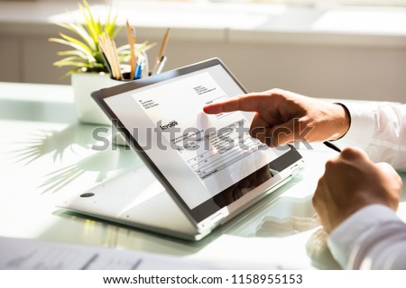 Close-up of a businessman's hand examining invoice on laptop Royalty-Free Stock Photo #1158955153