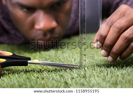 Close-up Of A Man Cutting Green Grass Measured With Ruler Royalty-Free Stock Photo #1158955195