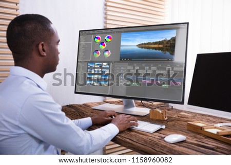 An African American Businessman Editing The Video On Computer Over The Wooden Desk