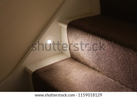 A modern stair case painted white, with brown carpet and spotlights on the sides