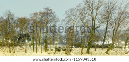 HDR winter photo of trees on the bank of a river with snow covering the ground 