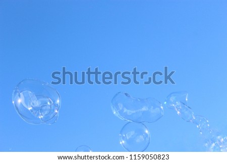 An artistically enhanced and manipulated photograph of a group of bubbles floating through the air in front of a blue background. 
