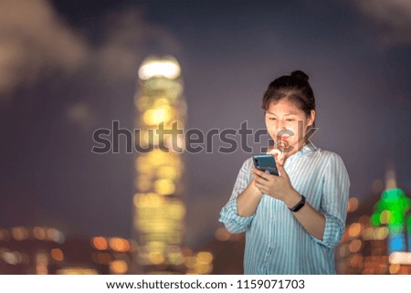 Woman using smartphone in front of Victoria Harbor, Hong Kong