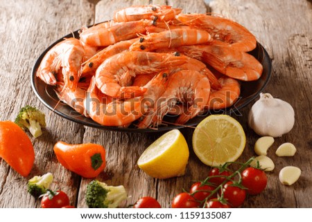 Dish with large shrimp and fresh vegetables close-up on a wooden table. horizontal
