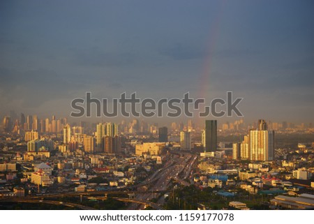 scenic of cityscape with rainbow after rainy skyline and golden sun light on building