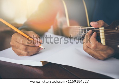 songwriter thinking and writing notes,lyrics in book at studio.man playing live acoustic guitar.concept for musician creative.artist composer in work process.people relaxing time with instrument Royalty-Free Stock Photo #1159184827