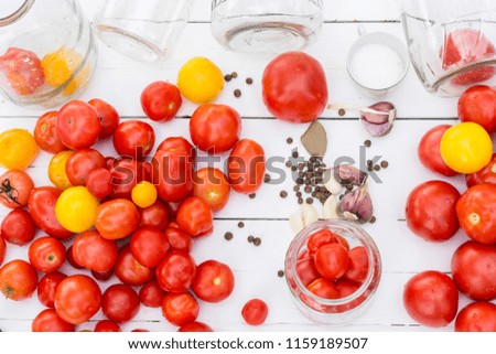 Tomato prepared for preservation on a white wooden background with seasonings and jars near .Top view