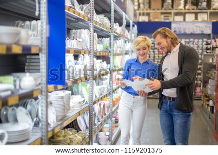 Young couple shopping. Handsome young couple choosing a gift for friends birthday, deciding what dinner service to buy. Consumerism, shopping, lifestyle , fashion
