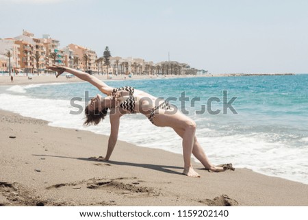 Young woman practicing yoga on the shore of the sea