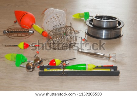 Composition with accessories for fishing on a wooden background. Fishing tackle - floats, hooks and baits on a wooden background. fishing tackles