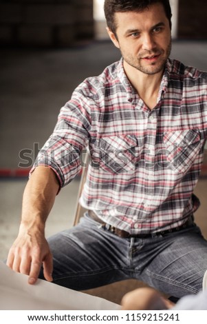handsome guy in casual clothes pointing at the blueprint while sitting with colleagues. close up cropped photo