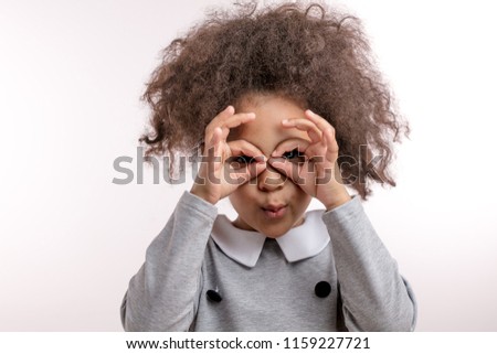 joyful kid with funny hair is looking through the fake glasses. have fun. entertainment concept