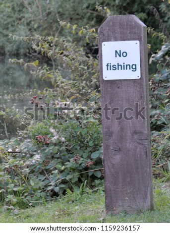 A no fishing sign on a wooden post.