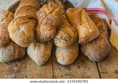 Various of french country breads and linen napkin on rustic wooden background