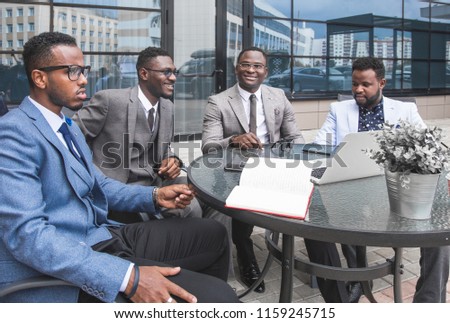 Group of happy diverse male and female business people team in formal gathered around laptop computer in bright office against the background of a glass building