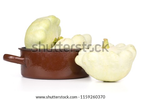 Group of three whole summer white pattypan squash in a brown cast iron pan isolated on white background