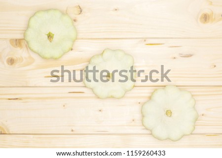 Group of three whole summer white pattypan squash in line flatlay on natural wood