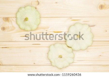 Group of three whole summer white pattypan squash flatlay on natural wood