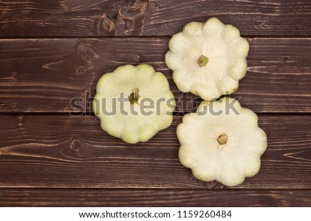 Group of three whole summer white pattypan squash flatlay on brown wood