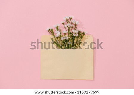 Opened envelope with flowers arrangements on pink background, top view. Festive greeting concept