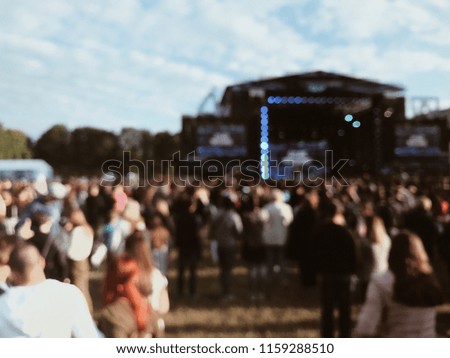 People dance at the music festival in the afternoon. Photo of crowd with raised up hands at music festival, audience applauding to musician band, music festival, happy youth. blurred photo