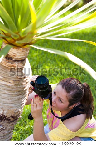 Beautiful young woman taking photos of a palm tree outdoors