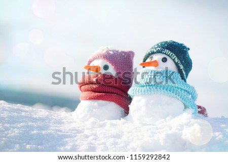 Two little snowmen the girl and the boy in knitted caps and scarfs on snow in the winter. Christmas card with a lovely snowman, copy space