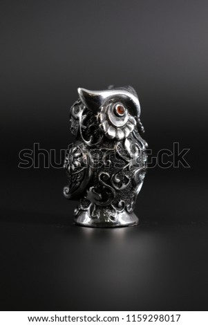 Owl a decorative figure, from different materials, against a dark background.