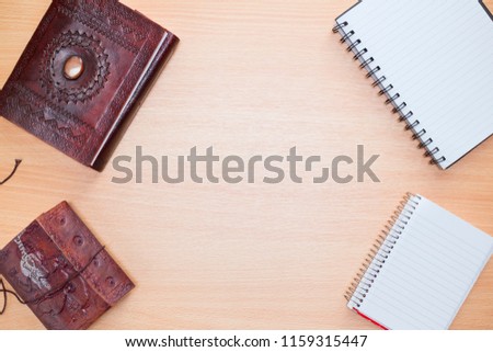 Flat lay photography. Old diary agendas with notebooks and blank space on the center of a wooden background. Top view of a desk. Various shapes and positions.