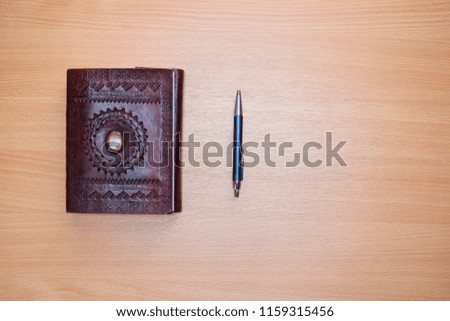 Flat lay photography. Old diary notebook agenda and grey elegant pen with blank space on a wooden background. Top view of a desk.