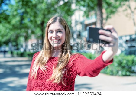 Blonde girl making selfie visiting city.