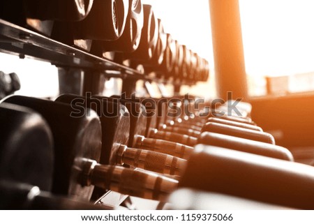 Black dumbbells set. Close up photo various metal dumbbells on the rack in sport fitness center against the sun light. Weight Training Equipment concept Royalty-Free Stock Photo #1159375066