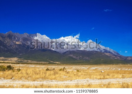 LIJIANG, YUNNAN PROVINCE, CHINA, Landscape view of Jade Dragon Snow Mountain with blue sky and trees, view from bottom of mountain