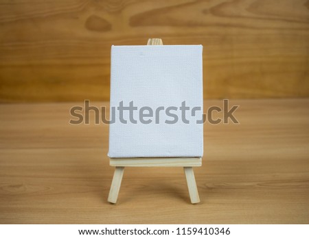 Blank canvas copy space on easel with wooden background