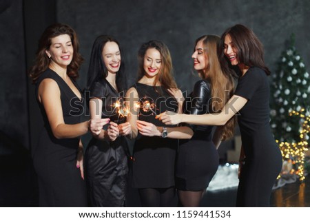 Beautiful girls in evening dresses with glasses of champagne to celebrate the New year