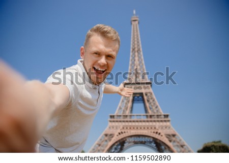 Happy man tourist is making photograph of Selfie on background of Eiffel Tower in Paris, France. Concept travel, rest.