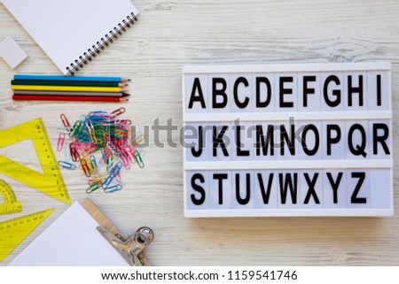 Back to school concept. Letters from A to Z. English alphabet on modern board and accessories for study over white wooden background, overhead view. From above, flat lay.