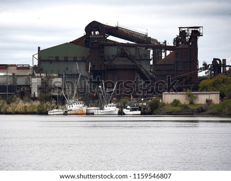 Old shrimp boats anchored in front of an old steel mill.