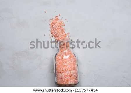 Pink Himalayan Salt in Vintage Glass Bottle Spilled on Grey Stone Tabletop. Wellness Spa Healthy Diet Nutrition Ayurveda Concept. Clean Minimalist Image Copy Space