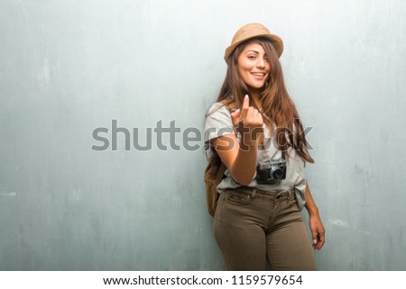 Portrait of young traveler latin woman against a wall inviting to come, confident and smiling making a gesture with hand, being positive and friendly