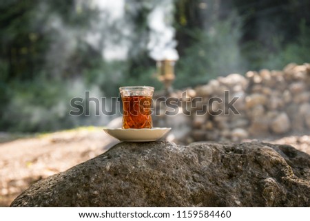 Eastern black tea in glass on a stone at forest. Eastern tea concept. Armudu traditional cup. Green nature background. Selective focus