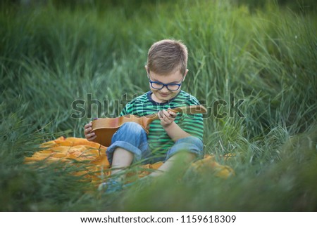 Attractive young boy outdoors with ukulele