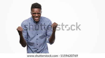 Young african american man wearing blue shirt celebrating surprised and amazed for success with arms raised and open eyes. Winner concept.