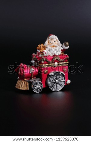 Santa Claus is traveling on a small red toy train.