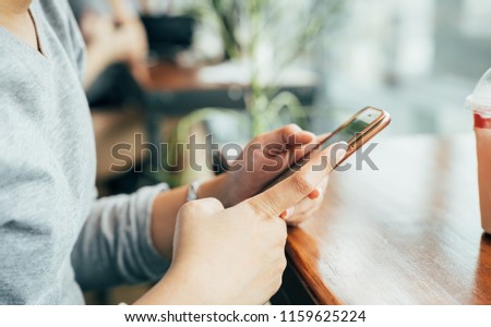 Woman hands holding using cellphone at coffee shop in the afternoon