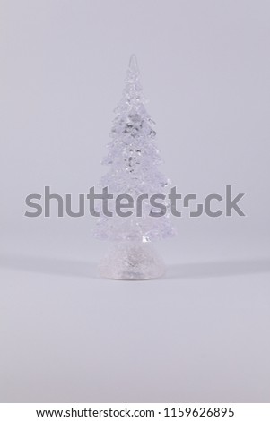 Stylized Christmas tree made of transparent material on a dark and light background.