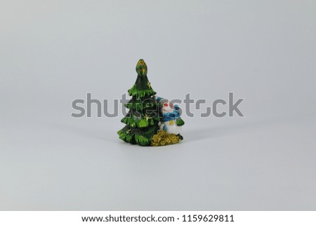 Stylized green Christmas tree and looking out from behind it snowman, subject shooting on a dark and light background.