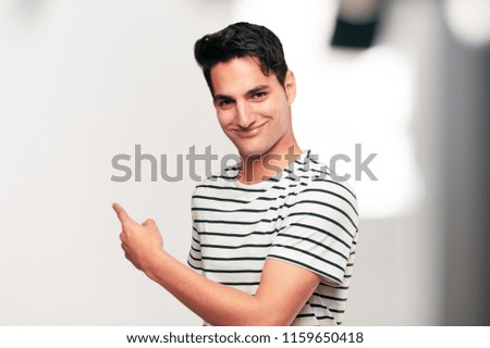 Young handsome tanned man smiling with a proud, satisfied and happy look, welcoming gesture or showing and recommending a concept, greeting you.