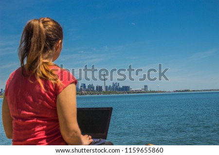 Freelancer woman while thinking and working on the shore of Ontario lake, Toronto